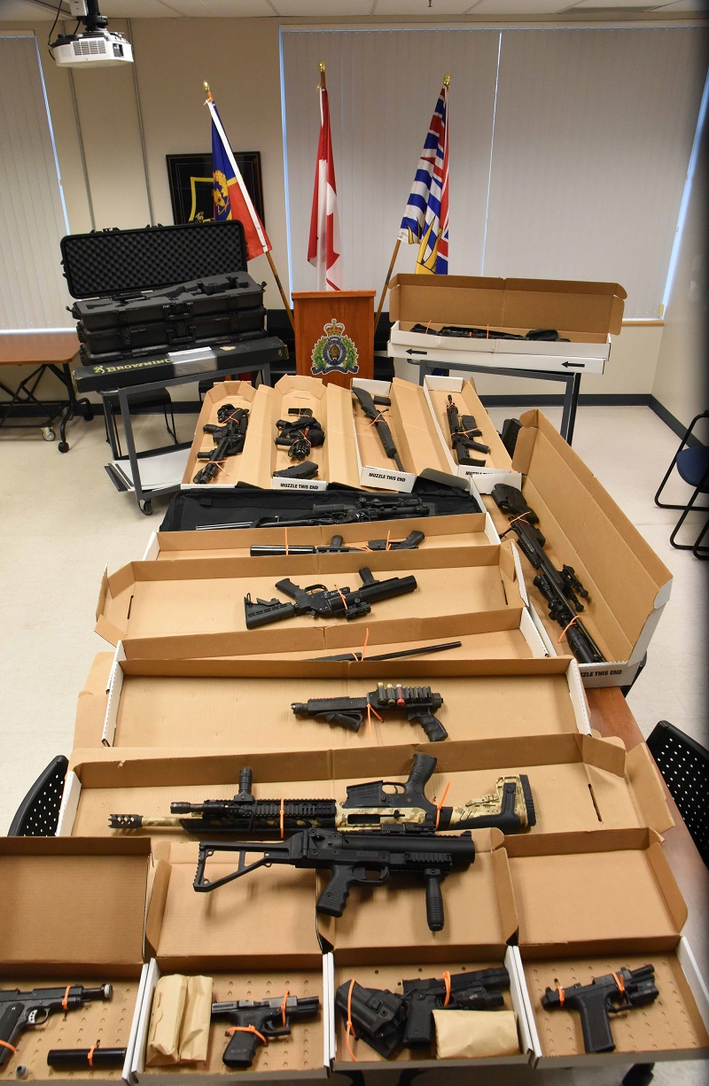 a large number of guns sit on a table infront of a a podium and flags