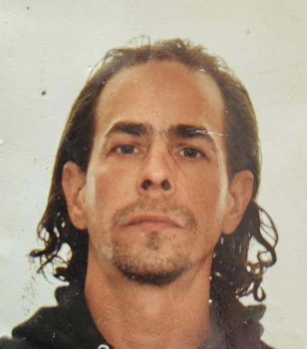 Photo of a caucasian male with brown shoulder length hair, receding hair line, blue eyes and a gotee. 