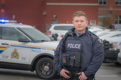 photo of police officer stading in front of a police vehicle 