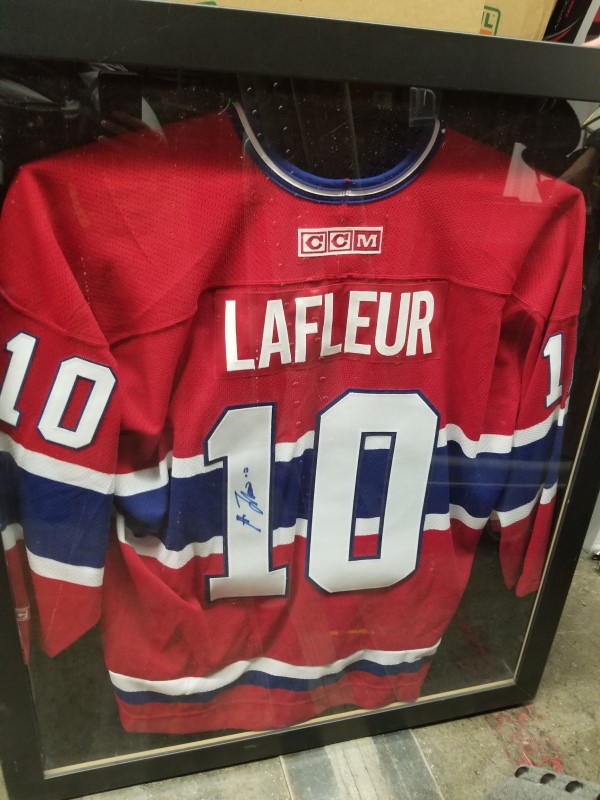 une boîte cadre contenant un chandail de hockey des Canadiens de Montréal autographié par Guy Lafleur;