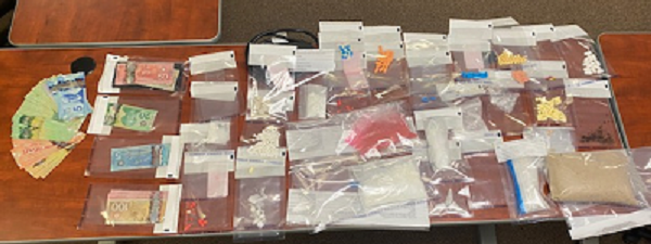 Assorted drugs and cash displayed on table