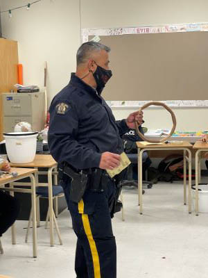 Le gend. Williams tient un cadre circulaire de tambour dans la salle de classe.