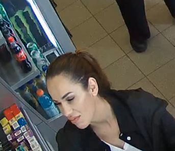 Photo of female suspect wearing black jacket, white shirt with dark hair in ponytail