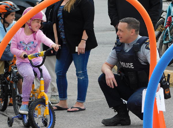 Police Officer kneeling down, talking to child on a bike