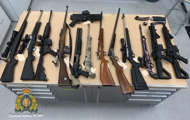 12 long guns and one hand gun displayed on a table. 