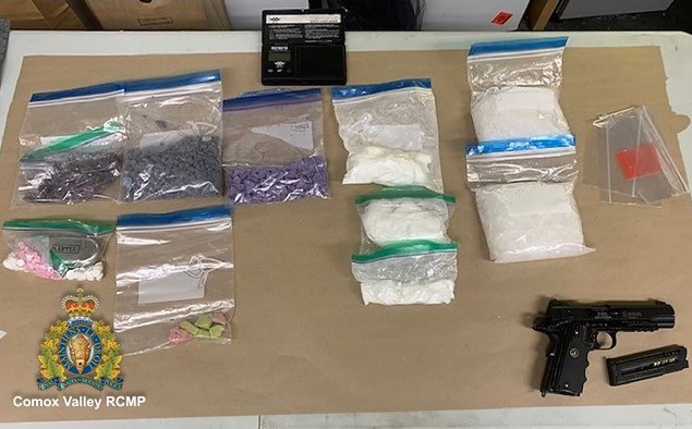 ten Ziploc bags displayed on a table.  Each bag contains illicit drugs seized by investigators. Also, a black handgun and magazine on display beside the bags. 
