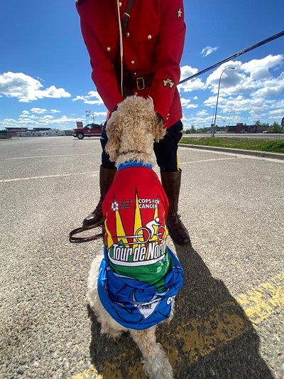 Photo of a police officer in red serge and a dog in a cycling jersey.
