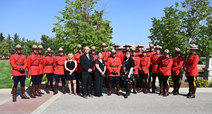 Four members of Cst. Shelby Patton's family pose with his troop mates, who are dressed in Red Serge, on a sunny day at Depot Division,