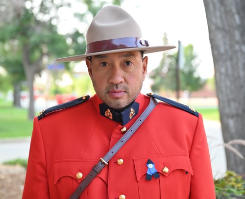 Cst. Derek Bay stands in his Red Serge near some trees at Depot Division in Regina.