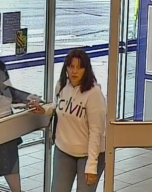 Femme suspecte ayant les cheveux brun foncé aux épaules et portant un chandail blanc à capuchon arborant le mot « calvin » devant. 