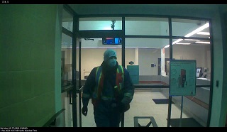 Photo of man wearing toque, blue coveralls, a mask and hi vis vest