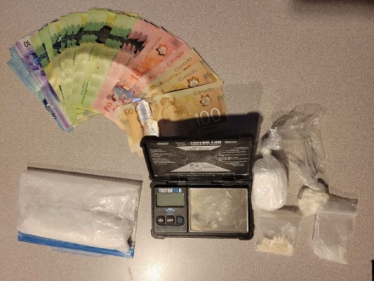Cash, scales and seized suspected drugs in baggies.