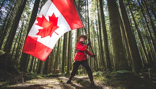 photo of RCMP officer in red serge in woods with canadian flag