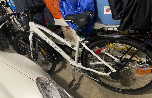 Photo of Narinder Sandhu’s white Infinity mountain bike with black storage rack on the back and the word Infinity branded on the main frame of the bike.