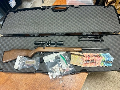 Drugs, thousands of dollars in Canadian currency, and a rifle with scope and ammunition in an open gun case. 